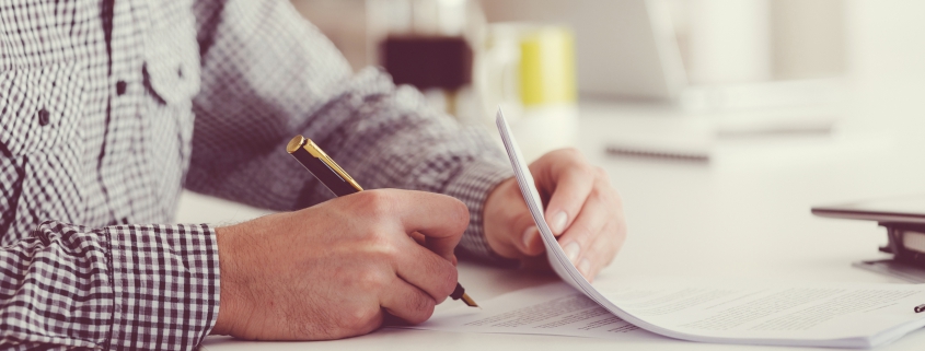 Male Business owner sitting at table and signing contract