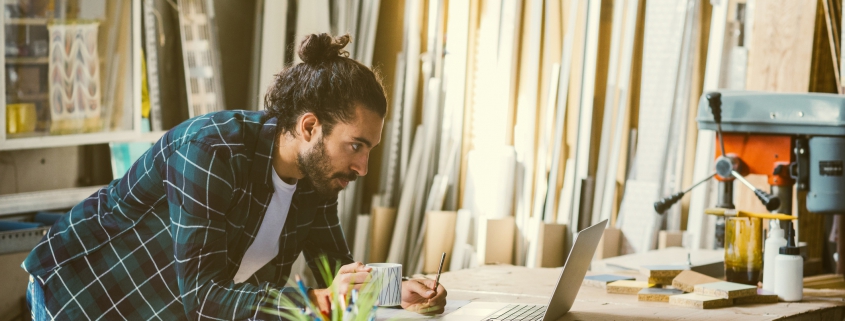 Male business owner reviewing delivery list on laptop
