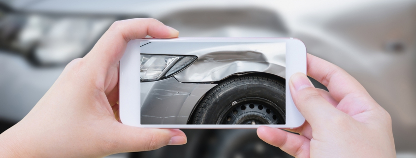 Person taking picture of a dented car with smart phone