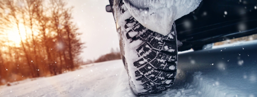 Car tires on winter road covered with snow.