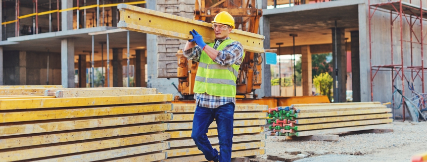 male construction worker carrying plank